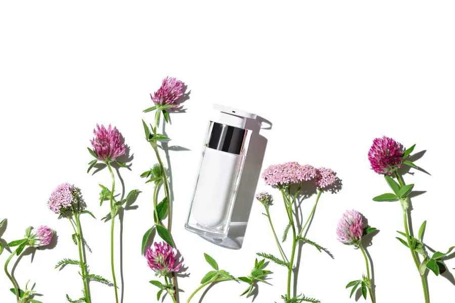 A skin care product with flowers below it.